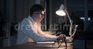 商人深夜在办公室笔记本电脑上打字